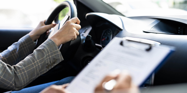 A male driving instructor and a happy student share a high-five inside the training car.