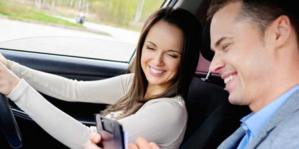 A driving instructor and student laugh together in the car, showcasing a relaxed and enjoyable learning atmosphere.