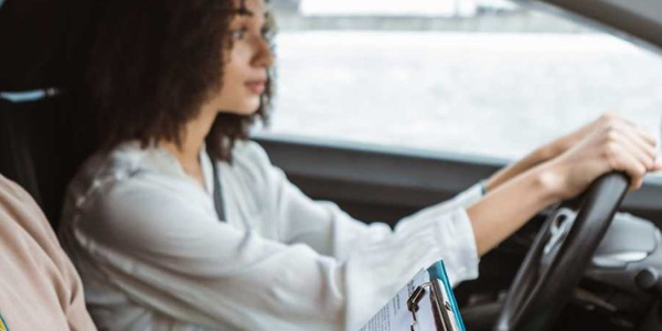 A student driver's perspective from behind the wheel, showing the road ahead and the car's dashboard during a lesson.