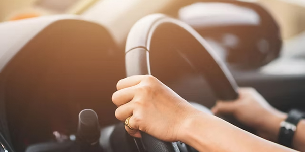 A focused student driver navigates a busy city street with their attentive instructor in the passenger seat of a dual-control car.