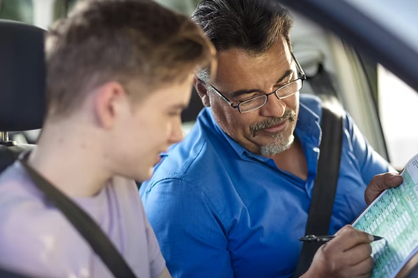 A close-up shot shows a student's hands confidently gripping the steering wheel, with the blurred road visible through the windshield.